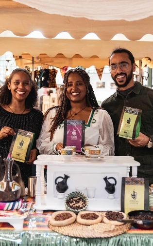 People smiling behand an food stand.
