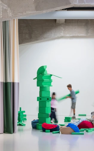 Een groep kinderen bouwt met groene blokken in verschillende vormen een toren.