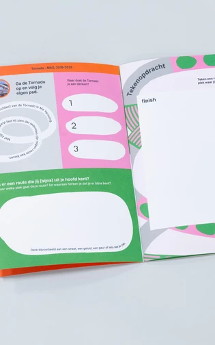 een opengeslagen boekje met kleurrijke vormgeving en illustraties ligt op een neutrale ondergrond