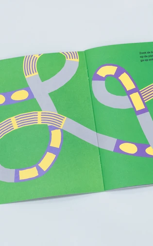 een opengeslagen boekje met kleurrijke vormgeving en illustraties ligt op een neutrale ondergrond