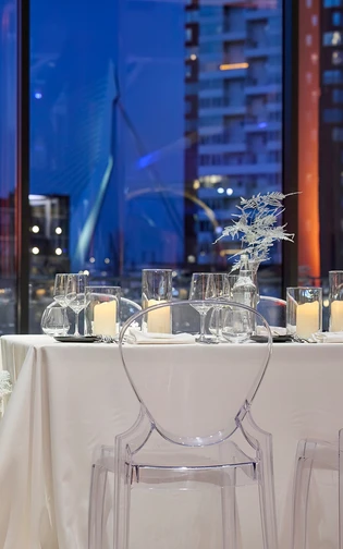 close up van een sfeervol gedekte tafel bij met grote ramen met uitzicht over de erasmusbrug