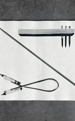A black-and-white photograph of experimental drawing tools arranged on a sheet of paper.