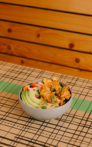 Een kom met verschillende ingredienten, kip, rijst, avocado