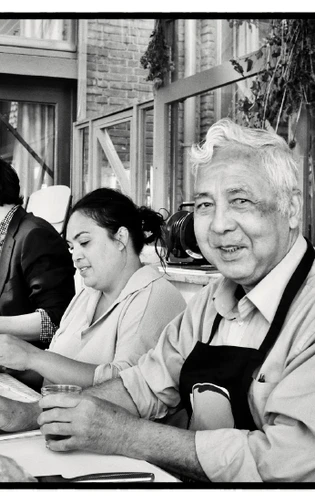 Three volunteers preparing food together at a community kitchen table.