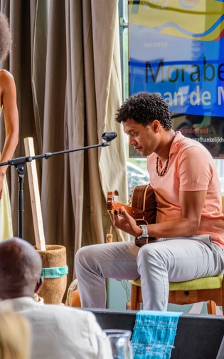 A singer performs on stage with live guitar accompaniment during a Cabo Verdean cultural programme.
