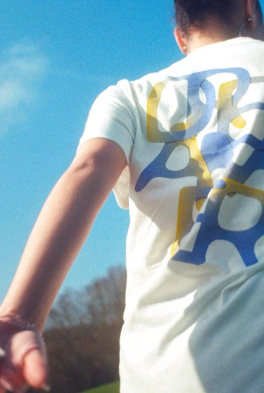 A group of people wearing white shirts with abstract blue and yellow designs running in a field