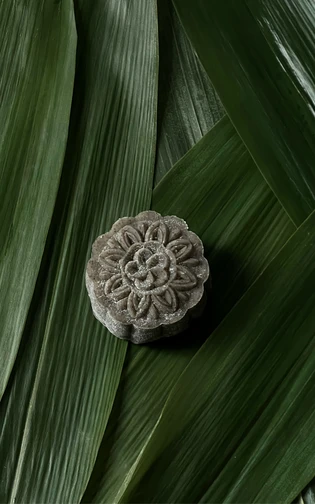a snow mooncake presented on a green banana leaf