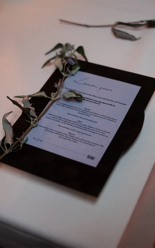 a diner menu and a elegant dried flower, presented on a white table cloth