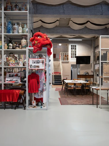 een ruimte met hoge kasten waar chinese vazen in staan, en een grote tafel met stoelen op een tapijt